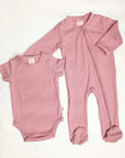 Pink baby onesie and bodysuit on a white background