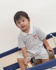 Child wearing Short-Sleeve Polo Romper - Stripes Sailor Mickey
sitting on a chair.