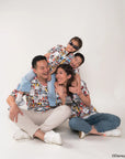 Family of four sitting on the floor against a white background, wearing matching tees