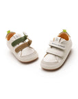 A pair of Tapioca white and green leather baby sneakers with a wide toe box and easy-strap closure.