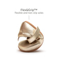 A champagne gold baby Mary Jane shoe being folded to demonstrate the ultra-flexible FlexiGrip non-slip rubber sole.