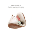 A white leather baby shoe with a pink heart being folded to show the flexible, non-slip rubber sole for first steps.