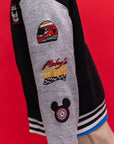 Close-up of a Bomber jacket Mickey 28 with racing-themed embroidered patches, including a helmet patch, 'Mickey's Speedway League' text, and a Mickey Mouse wheel patch.
