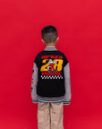 A child viewed from behind wearing a black and gray Mickey 28 Bomber jacket with a large Mickey Mouse '28' graphic on the back, standing against a solid red background.