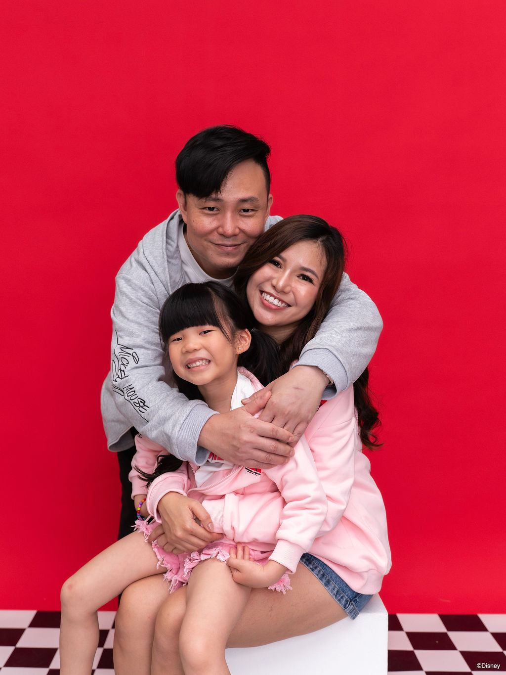 A family of three wearing our Carey Mickey racing Hoodies in grey and pink.