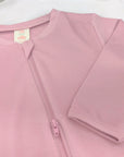 A closeup of pink baby sleepsuit on a white background