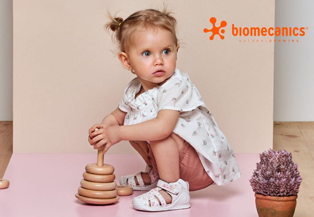 Biomecanics toddler wearing sandals playing with a toy.