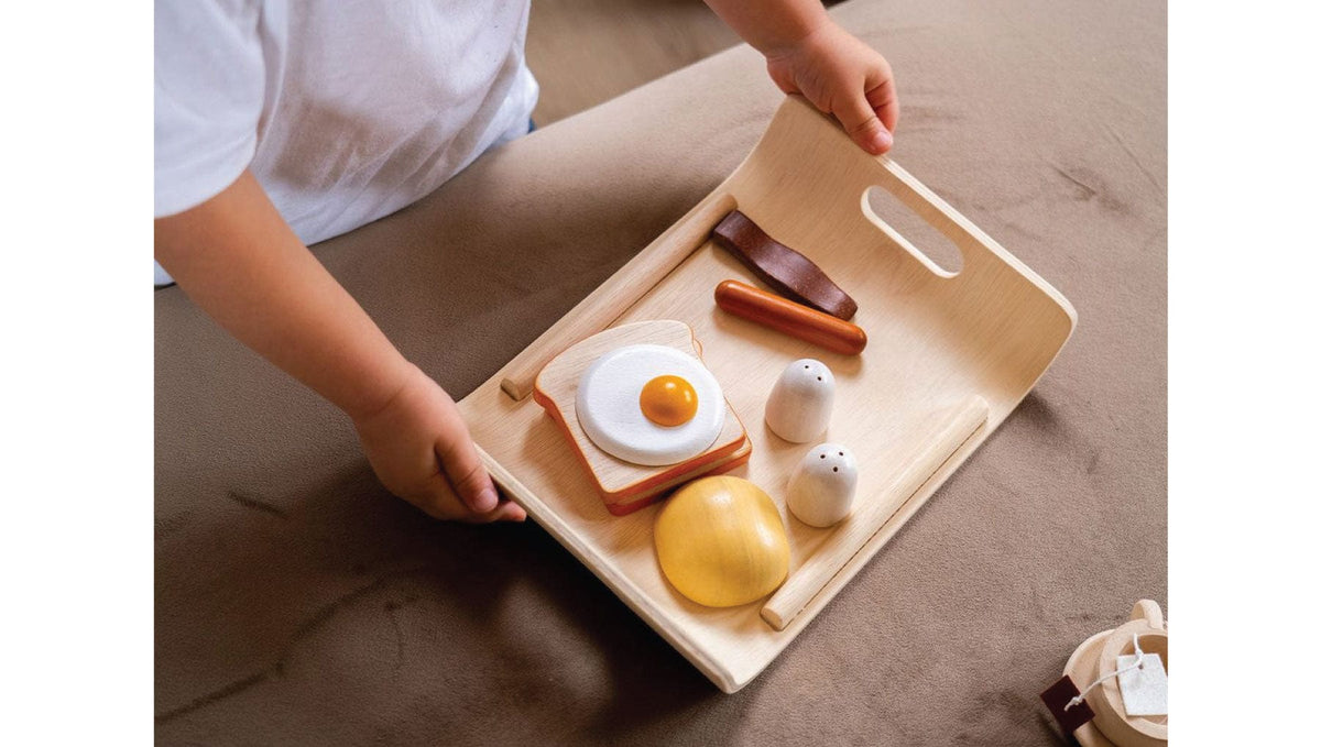 Child holding Plan Toys wooden breakfast tray