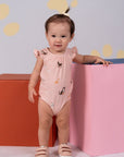 Baby girl in dog-print bodysuit, standing.