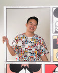 Person wearing adult pop comic mickey tee standing in front of Disney-themed artwork.
