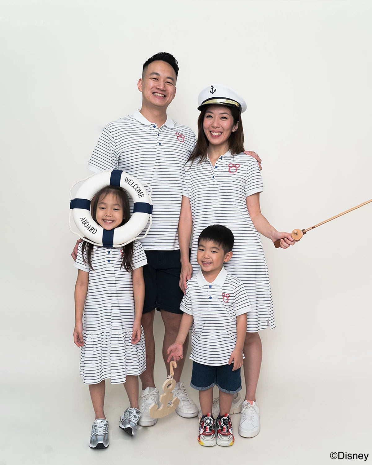 Family of four wearing matching stripes sailor mickey outfits with a white background