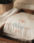 personalisable name embroidery on muslin swaddle with "Oliver" in Light Blue title case 