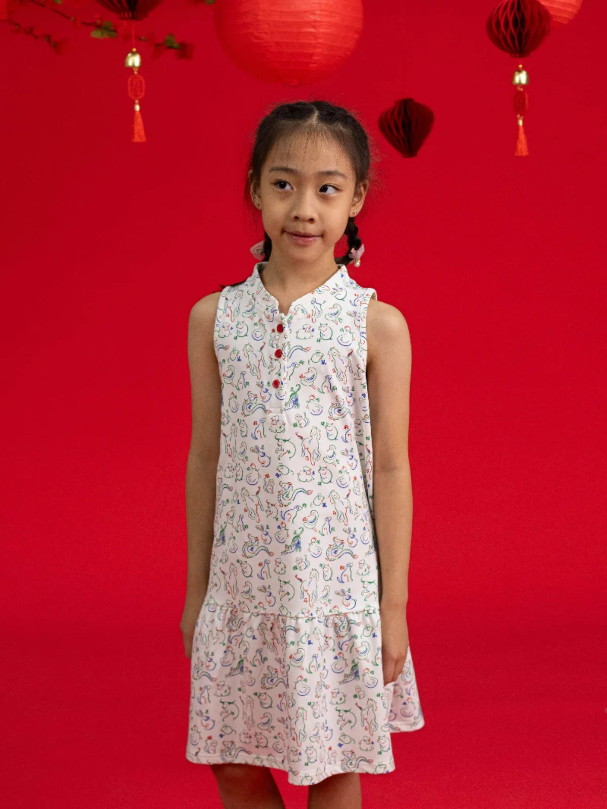 Girls' Naomi Cheongsam by Elly in Zodiac Mahjong print against a red background.