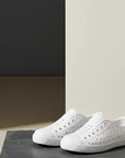 White slip-on shoes on a gray surface with a neutral background