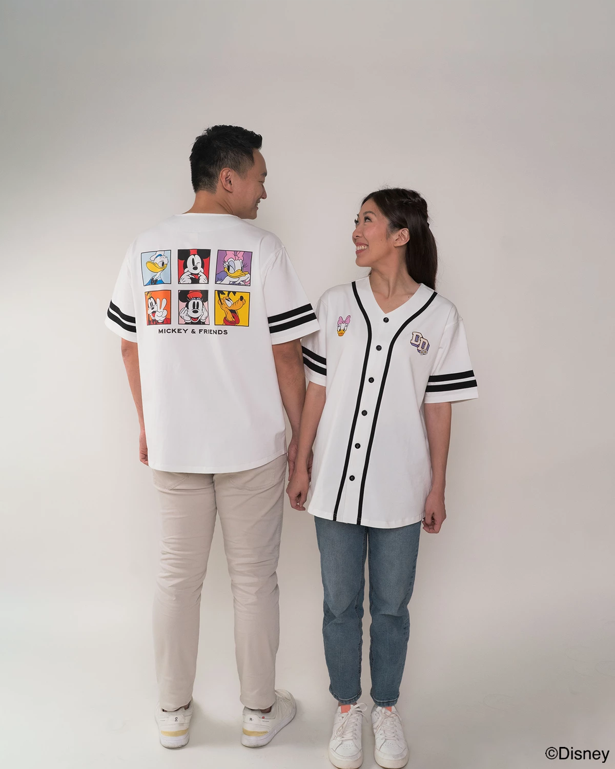 parents  wearing matching white baseball jerseys with pop mickey and friends 