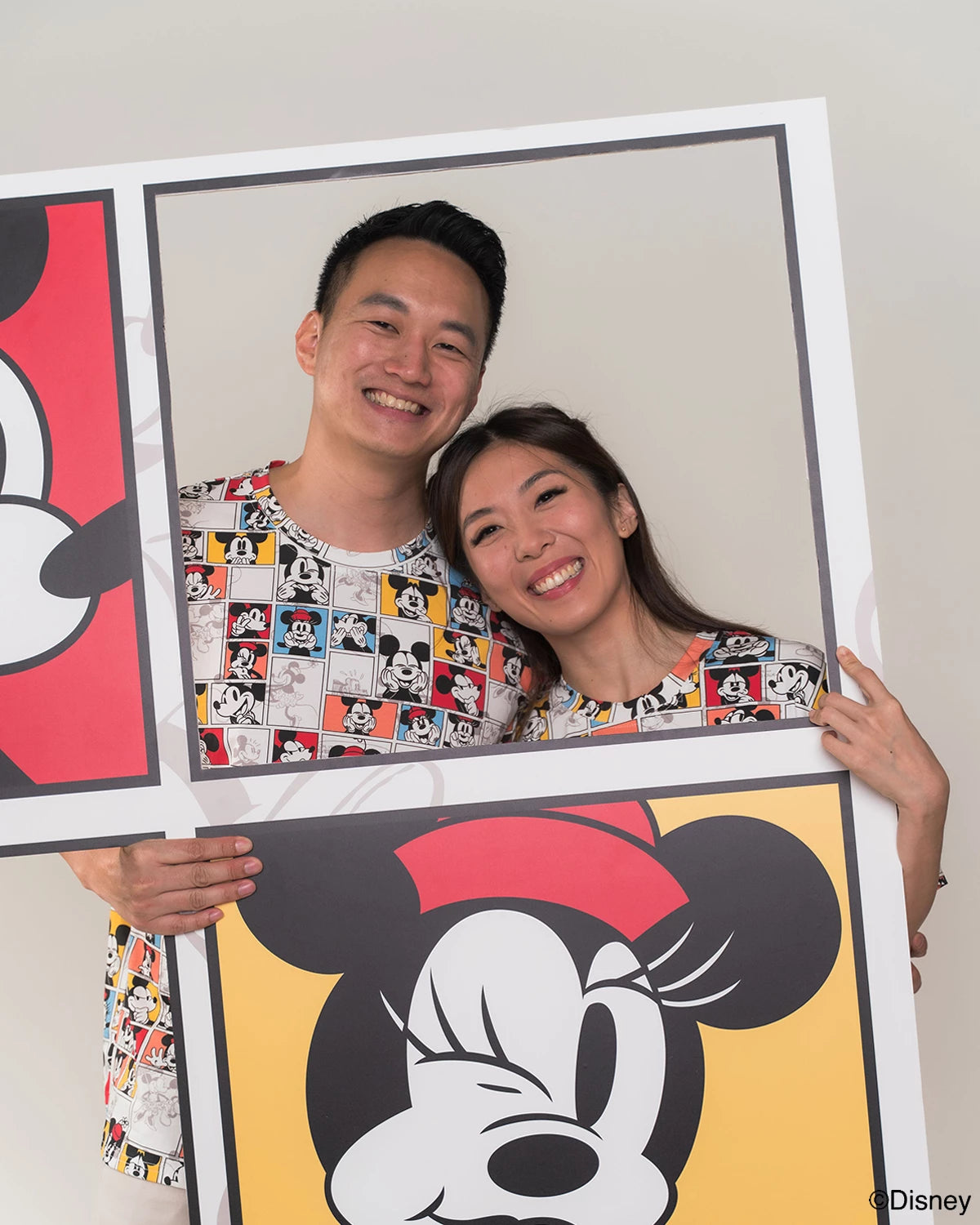 Two people holding up a large framed picture of a cartoon character in adult pop comic mickey tee 