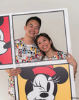 Two people holding up a large framed picture of a cartoon character in adult pop comic mickey tee 