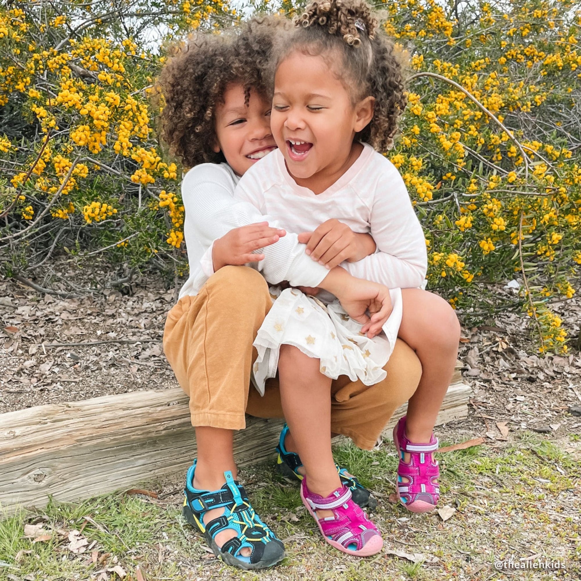 Two kids laughing, hugging outdoors