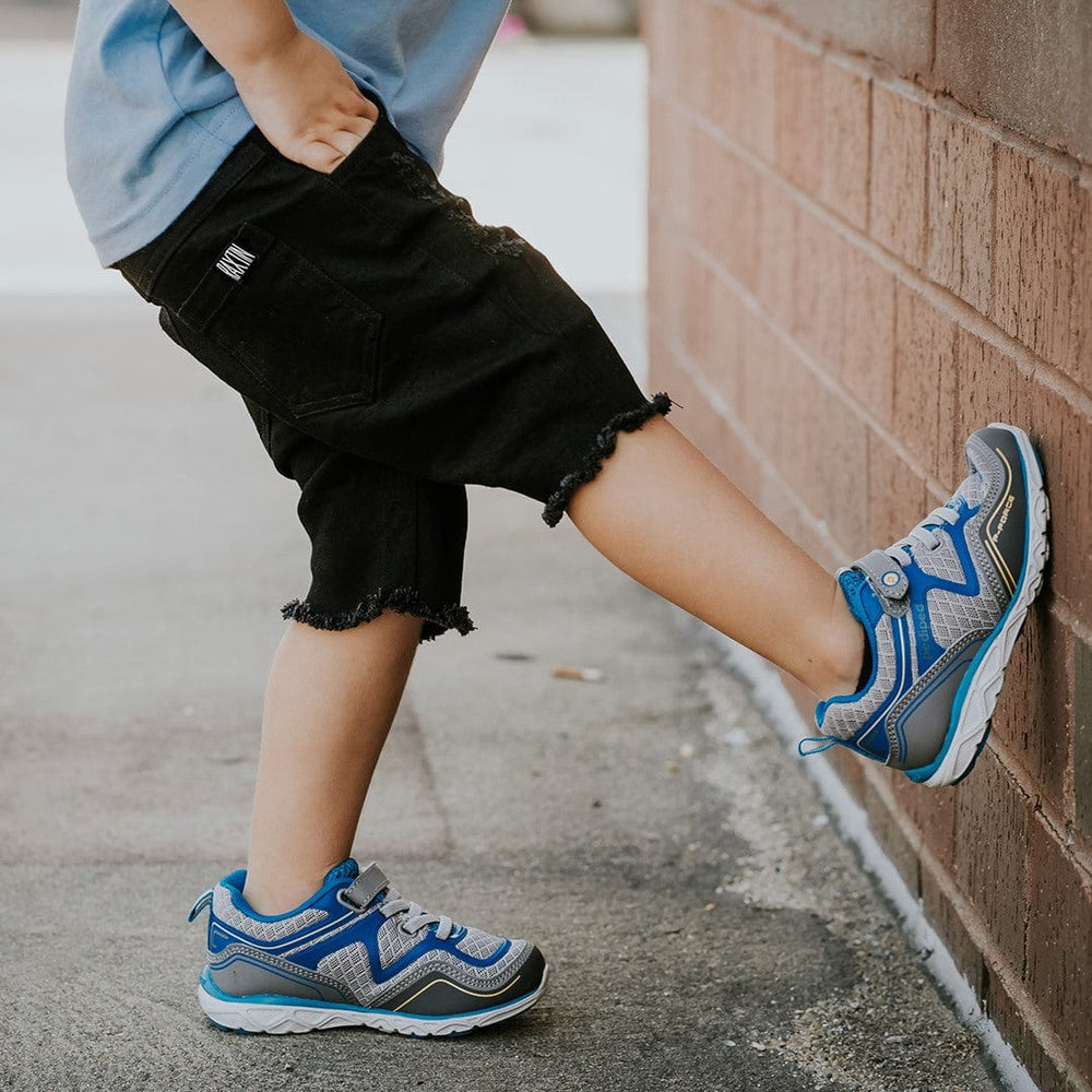 Pediped Force sneakers on child leaning against wall