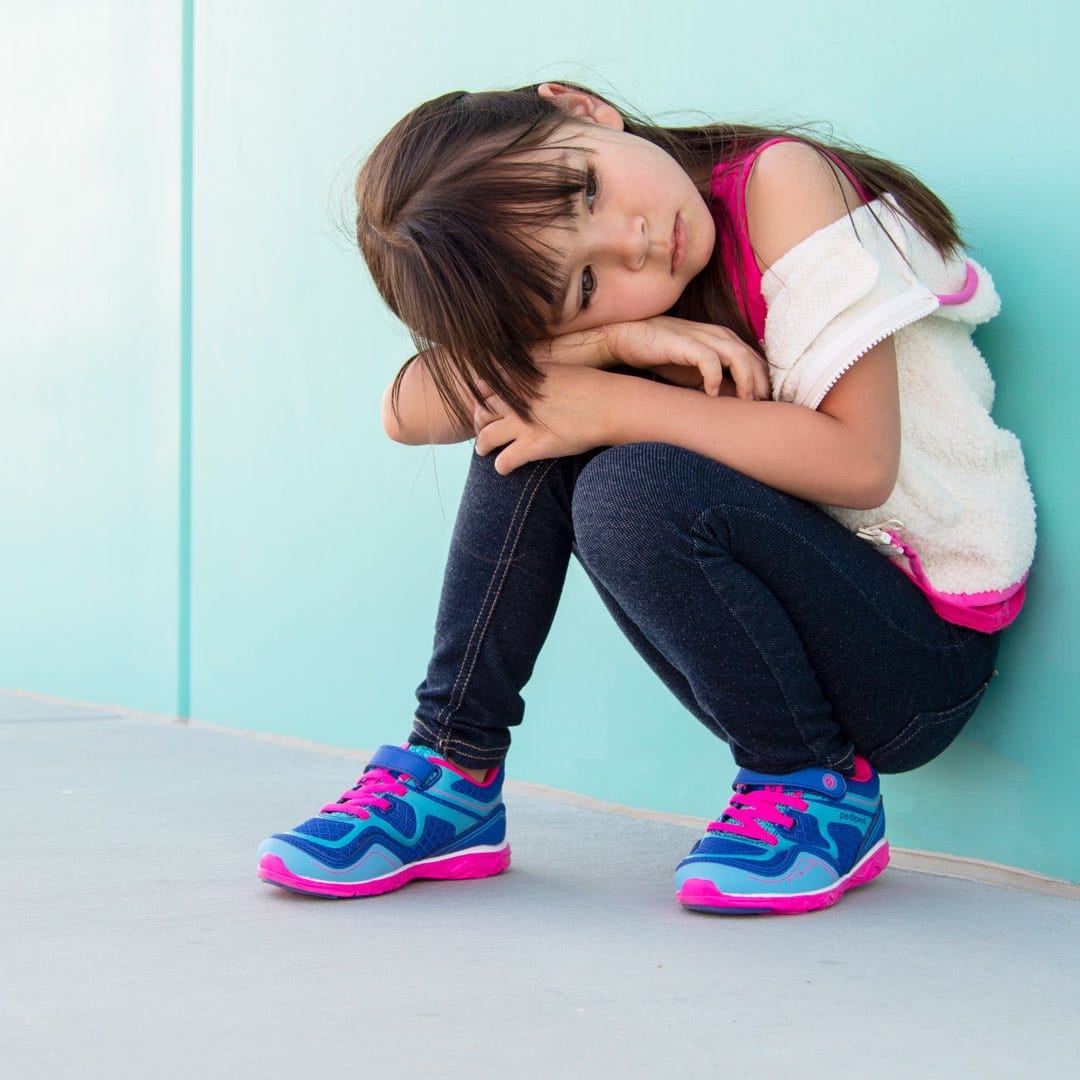 Girl in shoes sitting against wall