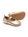 A pair of soft-sole champagne gold leather Mary Jane baby shoes with a flexible rubber sole and adjustable strap.